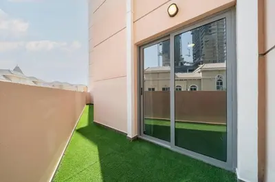 a balcony with green grass and a large window at Elegant JVC 1-Bed with Upgraded Interiors in Dubai