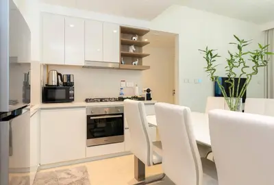 a kitchen with white cabinets and a table and chairs at CitiHome Luxury 1BR - Downtown Views 2 High Floor in Dubai