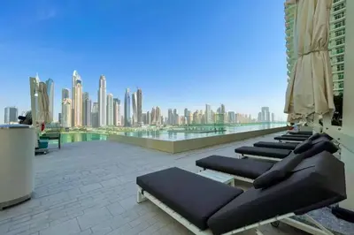 a row of lounge chairs on a roof with a city skyline at Elegant 2 Bed Beach Front Retreat in Dubai
