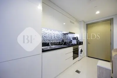 a kitchen with white cabinets and a glass wall at Bloomfields Magnificent STU Aykon City in Dubai