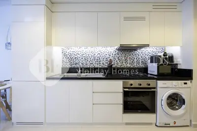 a kitchen with white cabinets and a washer and dryer at Bloomfields Magnificent STU Aykon City in Dubai