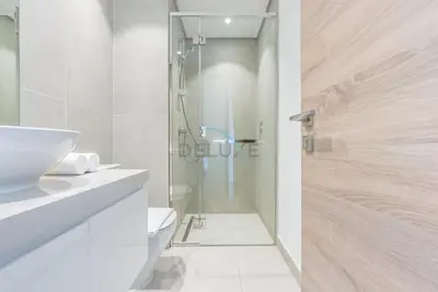 a white bathroom with a shower and a toilet at Stylish 2BR Stay Near Marina Beach and Ain Dubai, Steps from Shops and Restaurants, Studio One, Dubai Marina by Deluxe Holiday Homes in Dubai