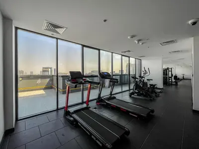 a gym with two exercise bikes and a large window at 2 Bed With Balcony Near World Renowned Golf Clubs in Dubai