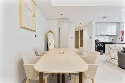 a dining room with a wooden table and chairs at 2 Bed With Balcony Near World Renowned Golf Clubs in Dubai