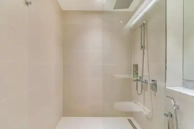 a white bathroom with a shower and a sink at GuestReady - Chic coastal living at Port de La Mer in Dubai