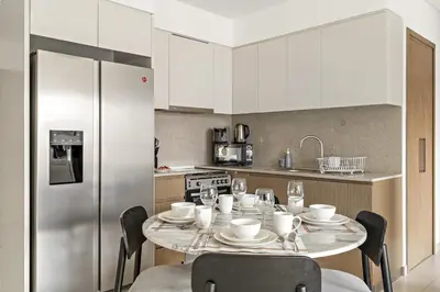 a kitchen with a table with chairs and a refrigerator at FIRST CLASS 2BR Burj Khalifa & Pool Views in Dubai