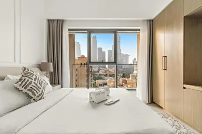 a bedroom with a large white bed with a large window at FIRST CLASS 2BR Burj Khalifa & Pool Views in Dubai