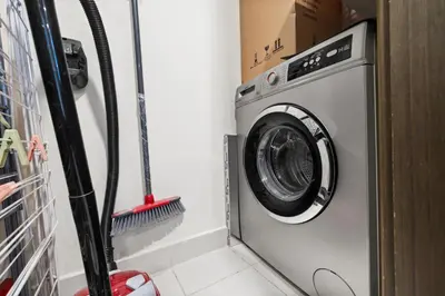 a washing machine in a room with a broom at Stunning 2BR in Downtown Partial Burj Khalifa View in Dubai