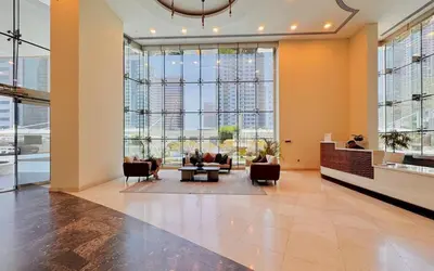 a lobby with couches and chairs and large windows at 2bed Canalside Home - Marina in Dubai