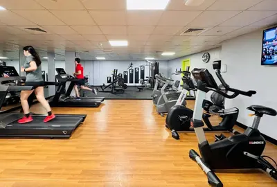 a woman running on a treadmill in a gym at 2bed Canalside Home - Marina in Dubai