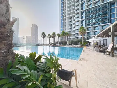 a swimming pool with palm trees and a large building at Luxury Canal View Studio with Pool Damac Maison Prive in Dubai
