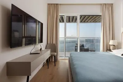 a bedroom with a bed and a desk and a large window at Elegant 2BR Apartment with Sea View in Dubai