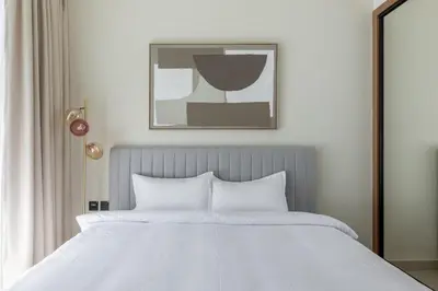 a bed with white sheets and a picture on the wall at Modern 1BR Apartment with City View in Dubai