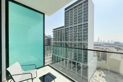 an apartment balcony with a chair and a view of a city at Modern 1BR Apartment with City View in Dubai