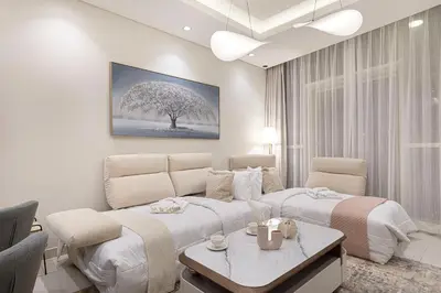 a living room with two beds and a tree at Maison Distinction Suites by Hostiva - Burj and Fountain View in Dubai