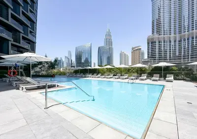 a large swimming pool with chairs and umbrellas in a city at Ultra-Luxury Burj & Fountain Suite at Address Opera in Dubai