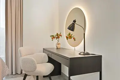a desk with a mirror and a chair and a lamp at Spacious & Cozy 2BD Apartment Peninsula One, Dubai in Dubai