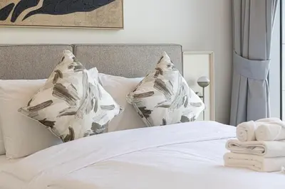 a bedroom with a bed with white sheets and pillows at New Luxury Canalfront 2 Bedroom Apartment with Burj Views in Dubai