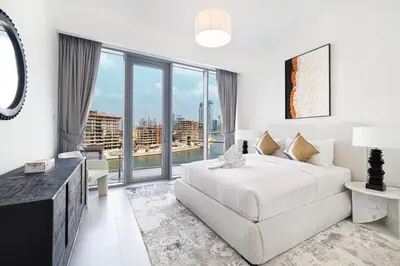 a white bedroom with a bed and a large window at New Luxury Canalfront 2 Bedroom Apartment with Burj Views in Dubai