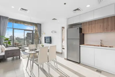 a kitchen and living room with a table and chairs at Chic Living 1 bedroom near Dubai Hills Mall in Dubai