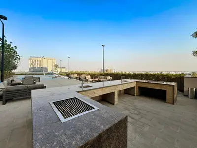a patio with a bench and tables and chairs at Chic Living 1 bedroom near Dubai Hills Mall in Dubai