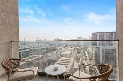 a balcony with a table and chairs and a view of a city at Chic Living 1 bedroom near Dubai Hills Mall in Dubai