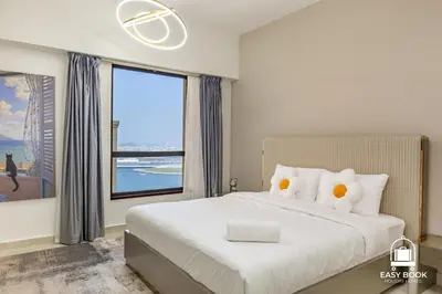 a bedroom with a large white bed with two pillows at Spacious 4BR Stay Sea JBR Views Sadaf 8 EB in Dubai