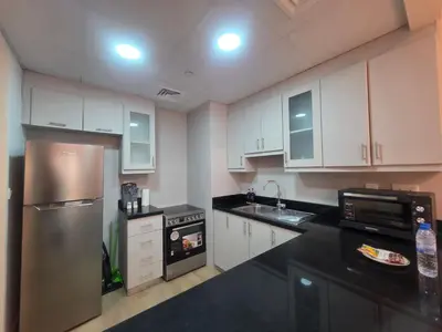 a kitchen with white cabinets and a stainless steel refrigerator at Stylish JBR Studio Beach View EB in Dubai