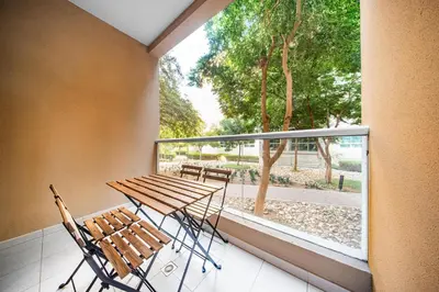 a balcony with a table and chairs and a window at Surrounded by Nature Near Internet & Media City in Dubai