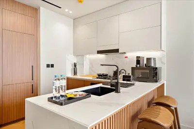 a kitchen with white cabinets and a sink at Modern 1BR Apartments by Nestovia in JVC with Pool and City Views in Dubai