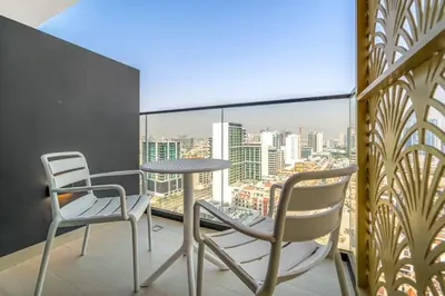 two chairs and a table on a balcony with a view at Modern 1BR Apartments by Nestovia in JVC with Pool and City Views in Dubai