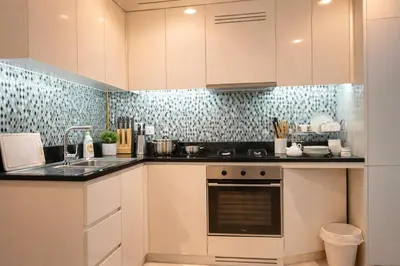 a kitchen with white cabinets and a sink at DAMAC Maison AYKON City C 3 Bedrooms Walk to Metro Sleeps 8 in Dubai