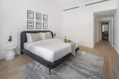 a white bedroom with a large bed and a bathroom at Frank Porter - Bay Square 1 in Dubai