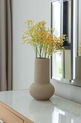 a vase with flowers in it sitting on a table at Frank Porter - Creek Crescent Tower in Dubai