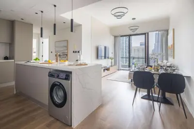 a kitchen and living room with a washing machine and a table at Frank Porter - Silverene Towers A in Dubai