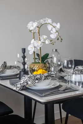 a table with plates and glasses and a vase with flowers at Frank Porter - Silverene Towers A in Dubai