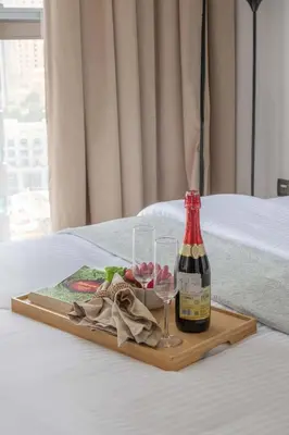 a tray with a bottle of wine and glasses on a bed at Frank Porter - No, 9 Dubai Marina in Dubai
