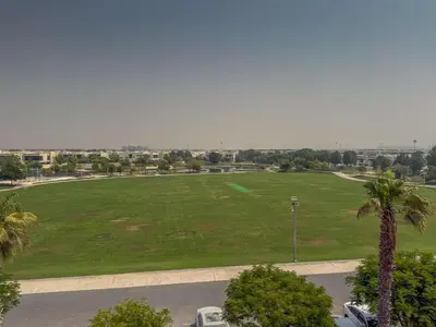 a large green field with palm trees and a parking lot at Frank Porter - Loreto 3 in Dubai