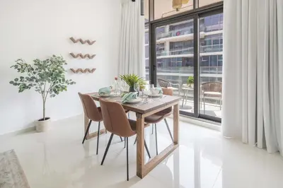 a dining room with a table and chairs and a window at Frank Porter - Loreto 3 in Dubai