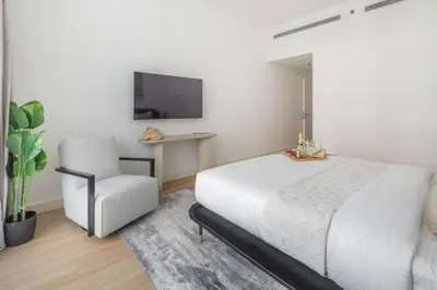 a bedroom with a white bed and a chair at Frank Porter - Bay Square 1 in Dubai