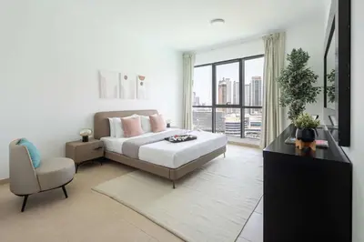 a bedroom with a bed and a chair and a window at Frank Porter - Residences Tower 1 in Dubai