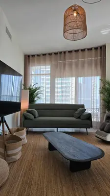 a living room with a green couch and a table at Private 2BR Oasis with Jacuzzi, Massage Chair, PS5, Steps Away From Opera, Dubai Mall, Dubai Fountains in Dubai
