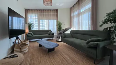a living room with a green couch and a tv at Private 2BR Oasis with Jacuzzi, Massage Chair, PS5, Steps Away From Opera, Dubai Mall, Dubai Fountains in Dubai
