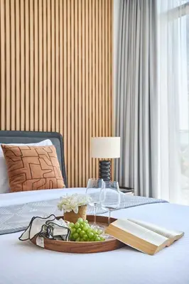 a tray of grapes and a book on a bed at Frank Porter - Azizi Park Avenue in Dubai