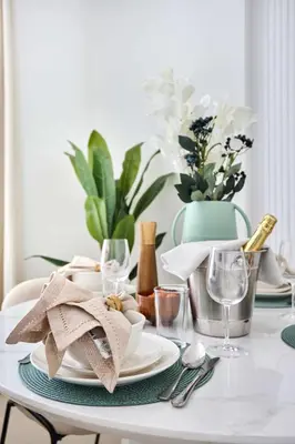 a white table with plates and glasses and plants at Frank Porter - Azizi Park Avenue in Dubai