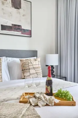 a table with wine glasses and a tray of grapes on a bed at Frank Porter - Sobha Hartland The Crest Tower C in Dubai