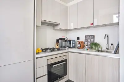 a kitchen with white cabinets and a stove top oven at Frank Porter - Sobha Hartland The Crest Tower C in Dubai