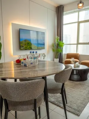 a living room with a wooden table and chairs at Stunning 2bd marina views prime location high floor in Dubai