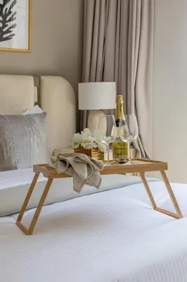 a table with two bottles and glasses on a bed at Frank Porter - Rosewater at Creek Beach 3 in Dubai