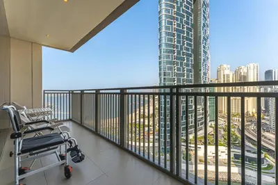 a balcony with a chair and a view of a city at Beachfront Vibe 2BR APT - Walk to JBR & Bluewaters in Dubai